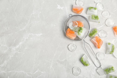 Photo of Frozen vegetables and ice cubes on gray table, flat lay composition with space for text