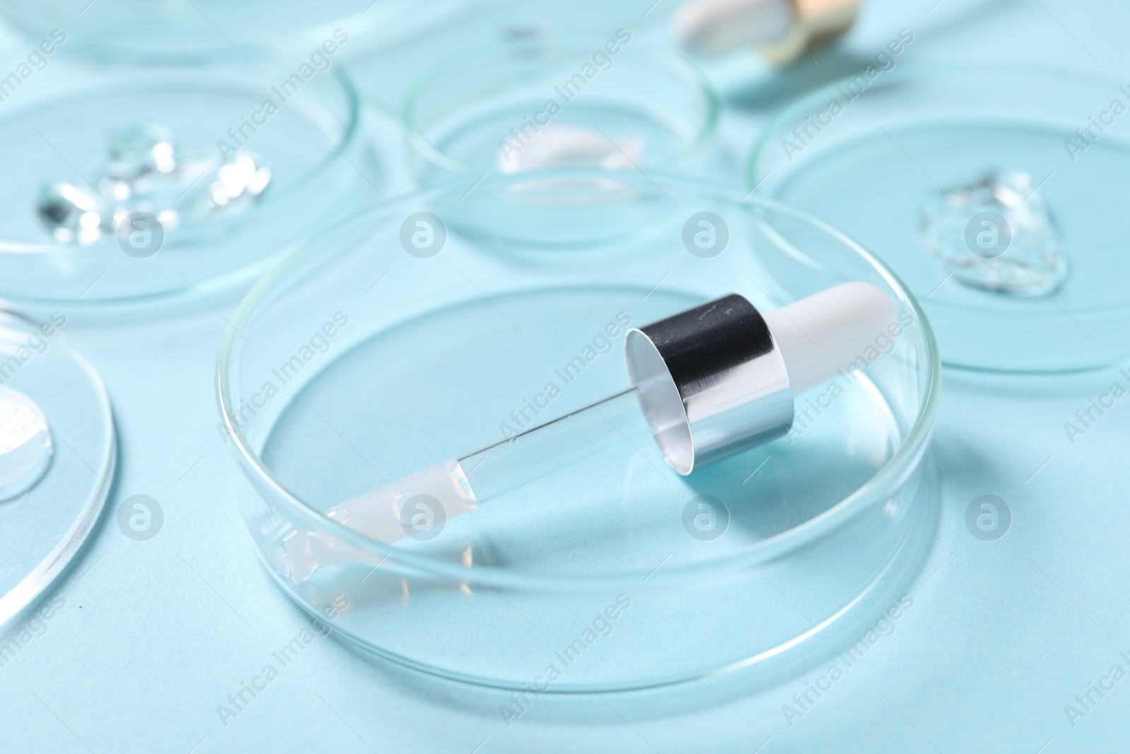 Photo of Petri dish and pipette with cosmetic serum on light blue background, closeup