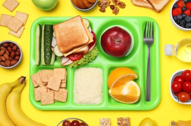 Flat lay composition with serving tray and tasty healthy food on yellow background. School dinner