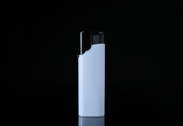 Photo of White plastic cigarette lighter on black background, closeup