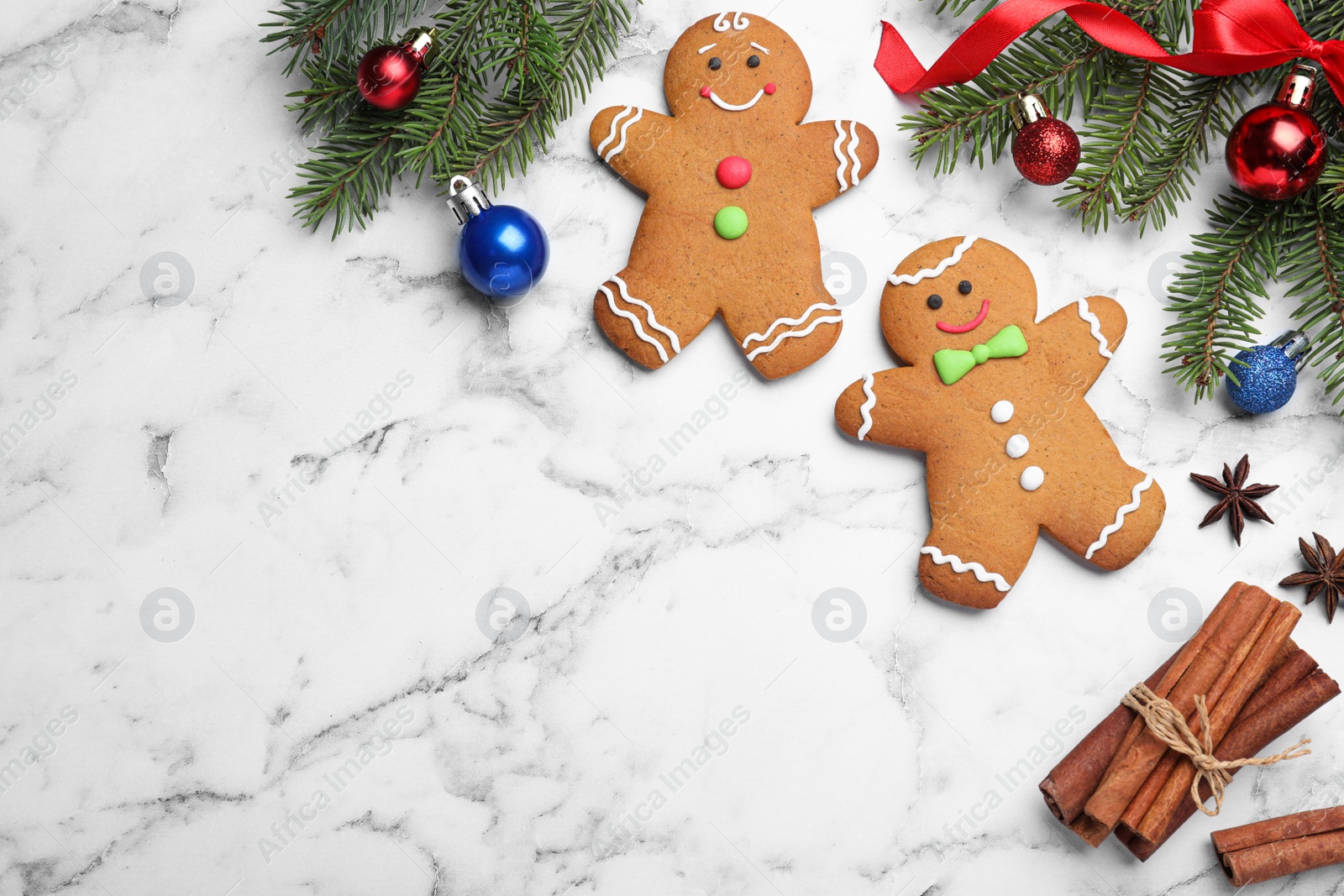 Photo of Flat lay composition with gingerbread men on white marble table, space for text