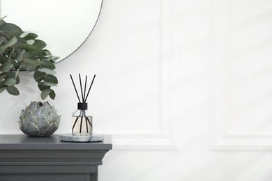 Photo of Reed diffuser and home decor on grey table near white wall. Space for text