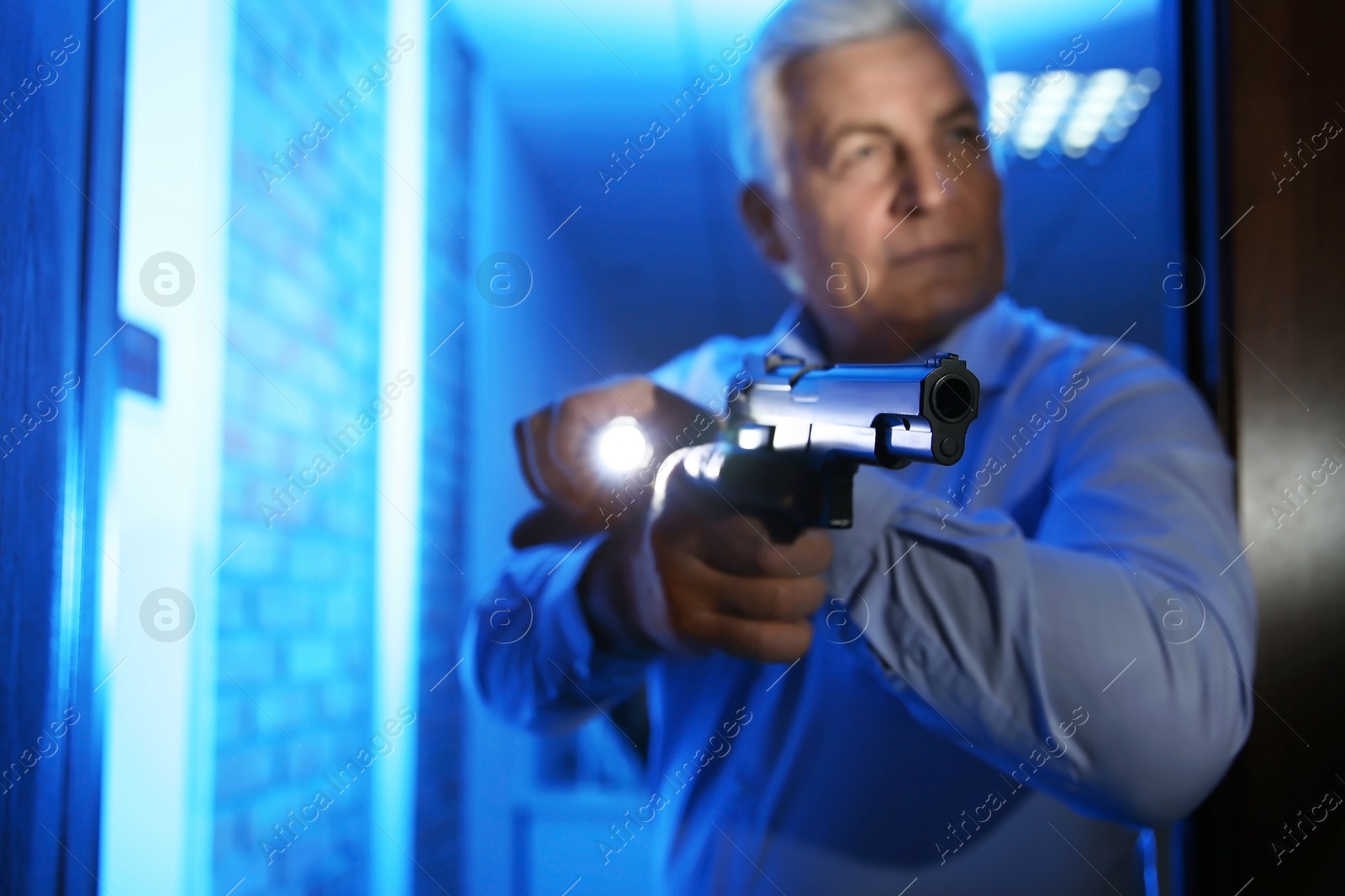 Photo of Professional security guard with gun checking dark room, focus on hand