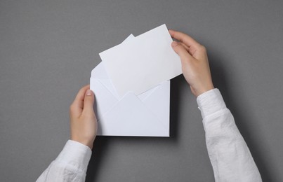 Photo of Woman taking card out of letter envelope at grey table, top view. Space for text