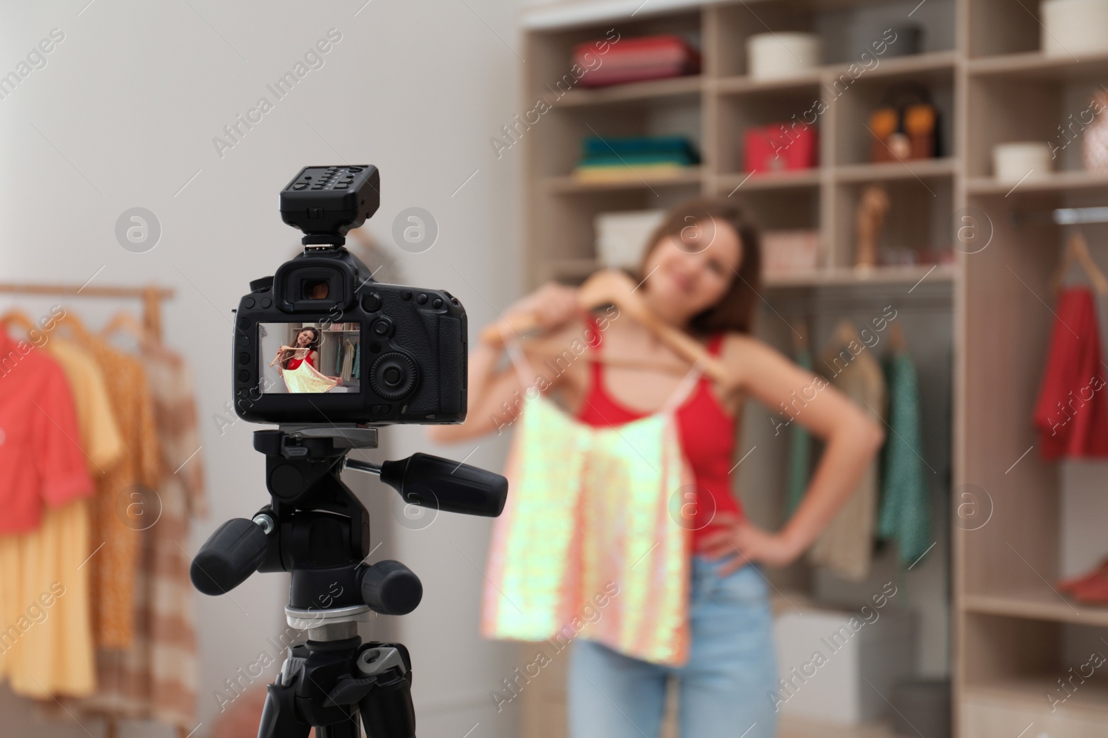 Photo of Fashion blogger recording new video in room, focus on camera