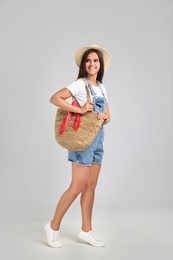 Photo of Young woman with stylish straw bag on light grey background