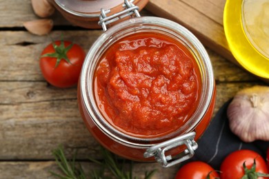 Photo of Homemade tomato sauce in jar on wooden table, top view