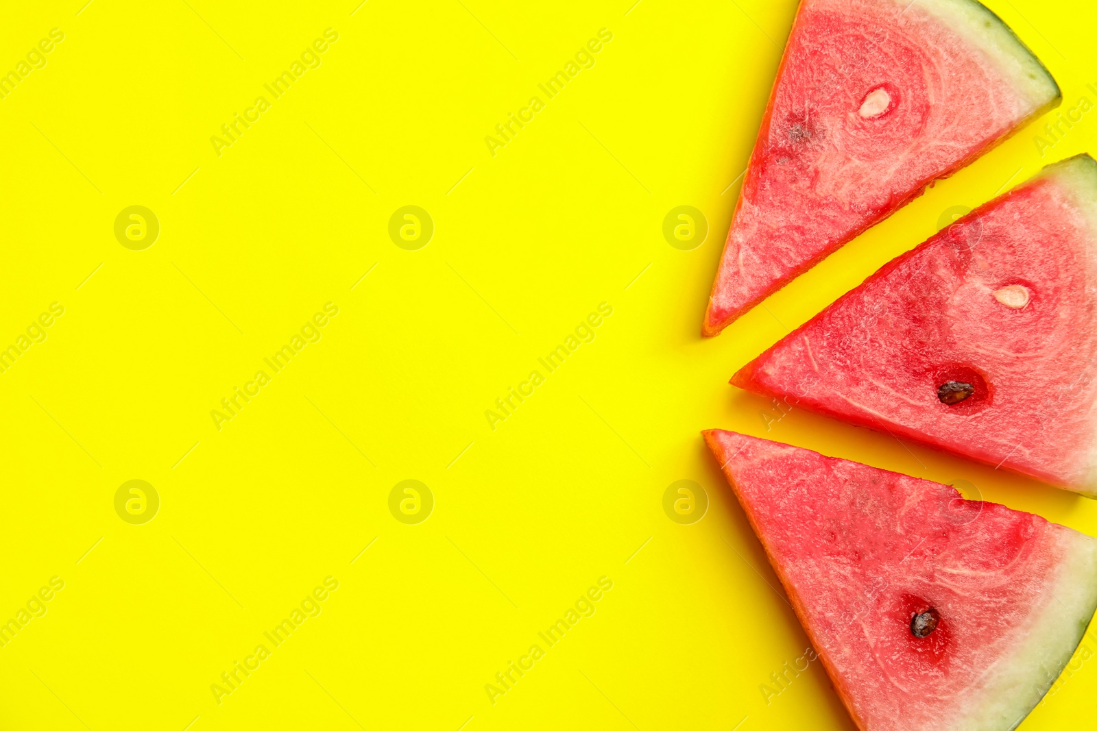 Photo of Slices of ripe watermelon on yellow background, flat lay. Space for text