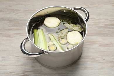 Different ingredients for cooking tasty bouillon in pot on white wooden table