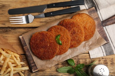 Photo of Delicious fried breaded cutlets served on wooden table, flat lay