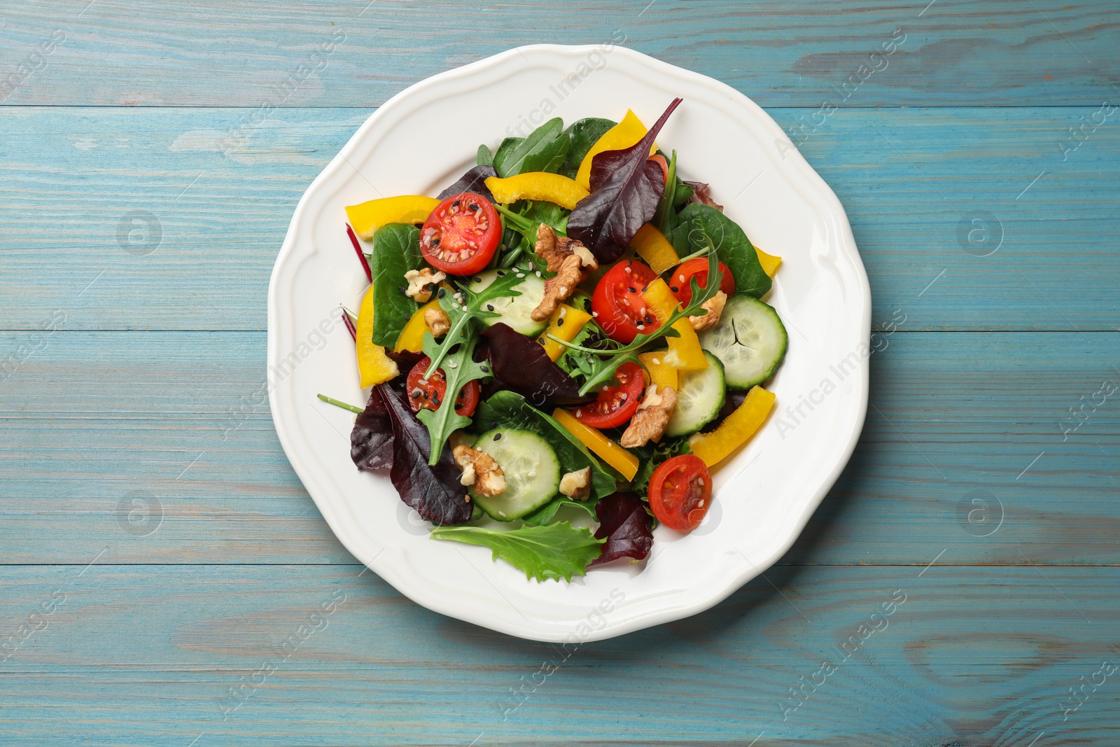 Photo of Tasty fresh vegetarian salad on light blue wooden table, top view