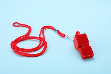 Photo of One red whistle with cord on light blue background