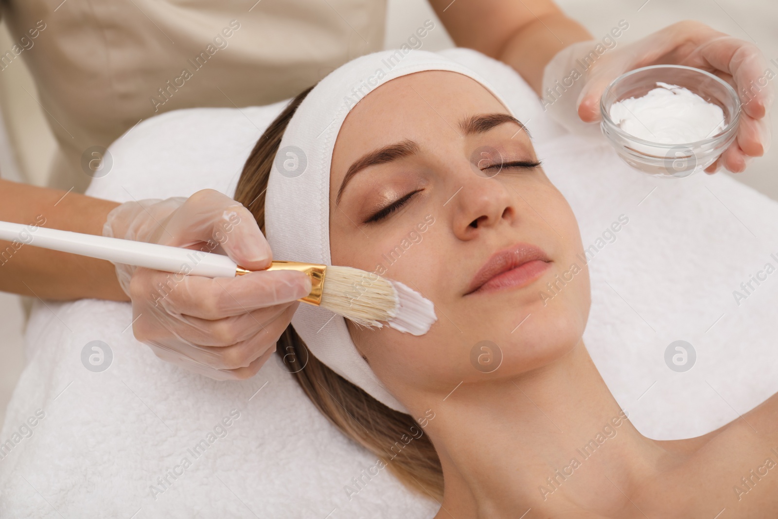 Photo of Young woman during face peeling procedure in salon