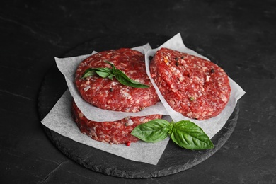 Photo of Raw meat cutlets for burger on black table