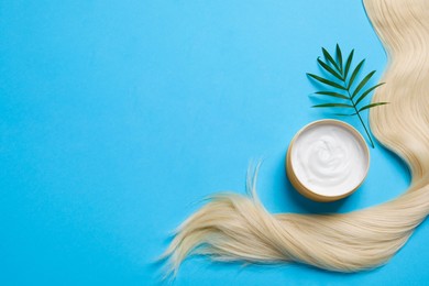 Photo of Lock of healthy blond hair, green twig and cosmetic product on light blue background, flat lay. Space for text