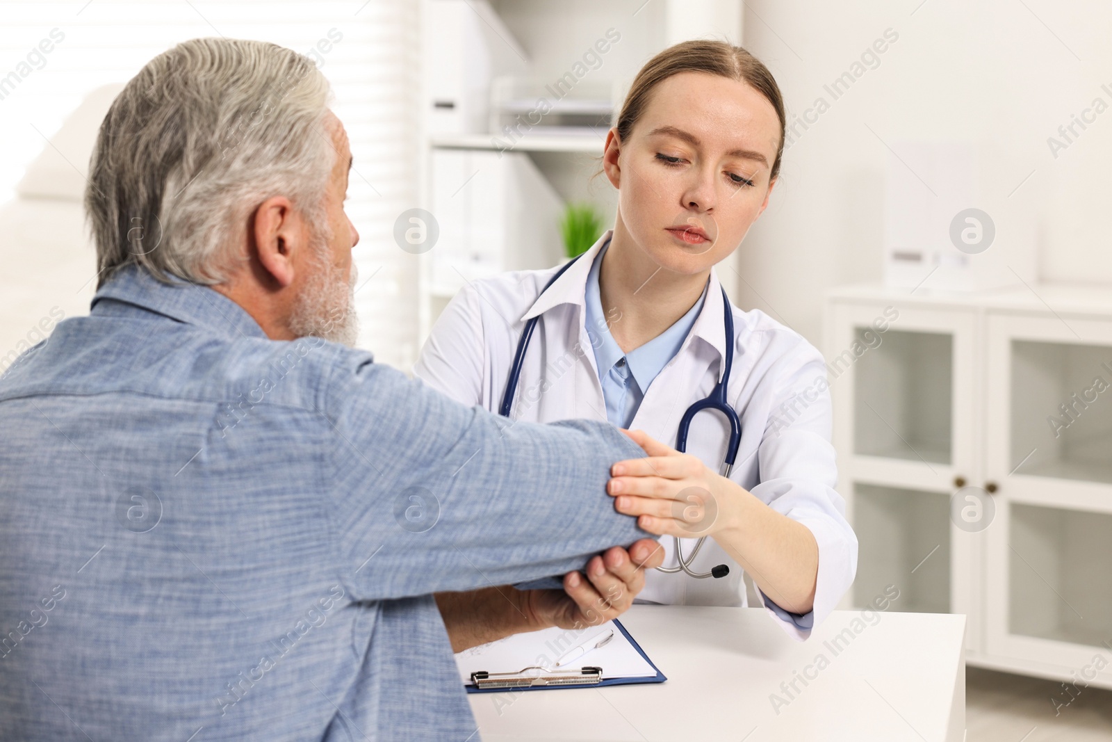 Photo of Arthritis symptoms. Doctor examining patient's elbow in hospital