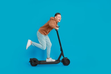 Photo of Emotional man riding modern electric kick scooter on light blue background