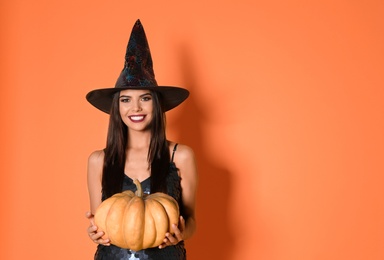 Photo of Beautiful woman wearing witch costume with pumpkin for Halloween party on yellow background, space for text