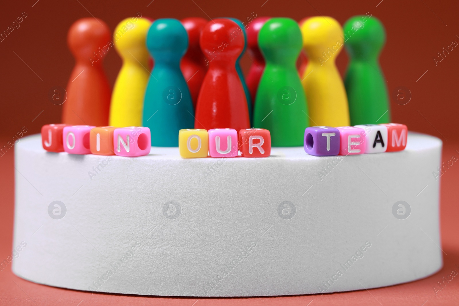 Photo of Colorful cubes with phrase Join Our Team and pawns on white round podium, closeup. Recruiter searching employee