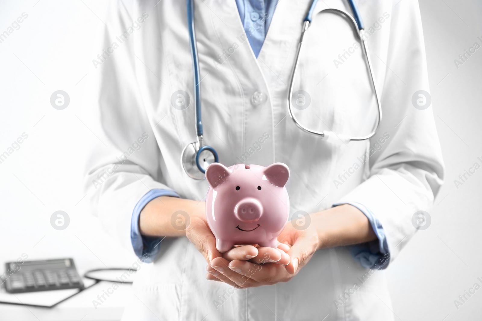 Photo of Doctor holding piggybank indoors, closeup. Medical insurance concept