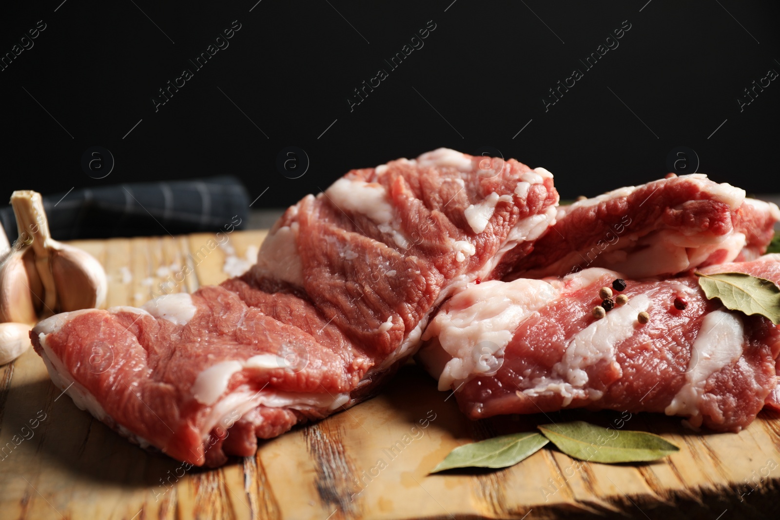 Photo of Raw ribs with bay leaves and salt on wooden board, closeup