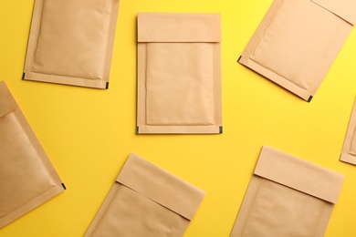 Photo of Kraft paper envelopes on yellow background, flat lay