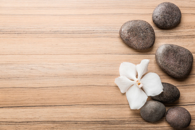 Stones and orchid flower on wooden background, top view with space for text. Zen lifestyle