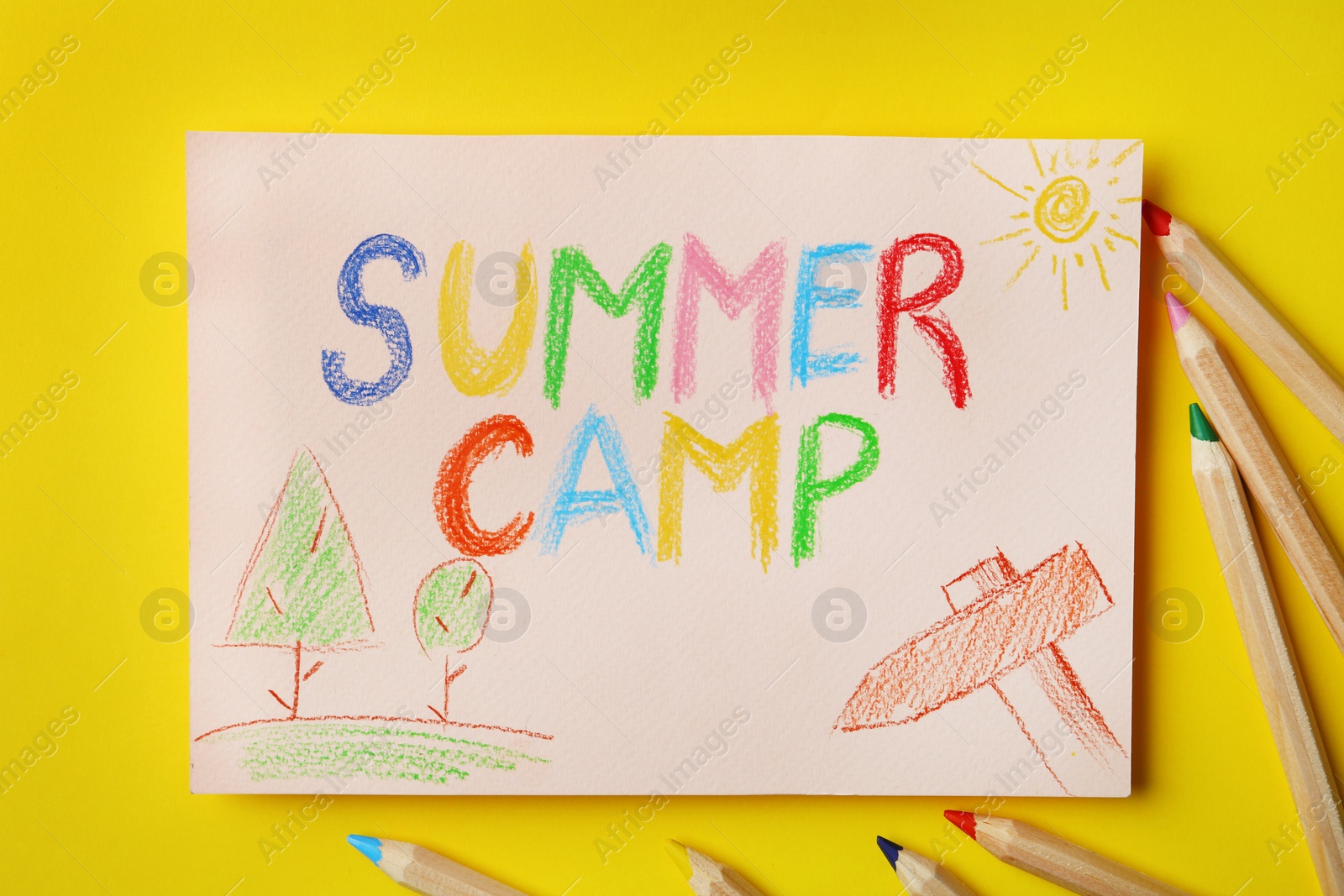 Photo of Paper with written text SUMMER CAMP, drawings and different pencils on color background, flat lay