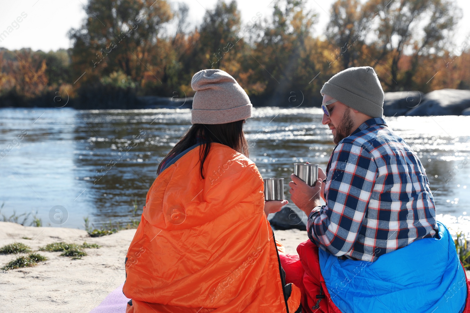 Photo of Campers sitting in sleeping bags on wild beach