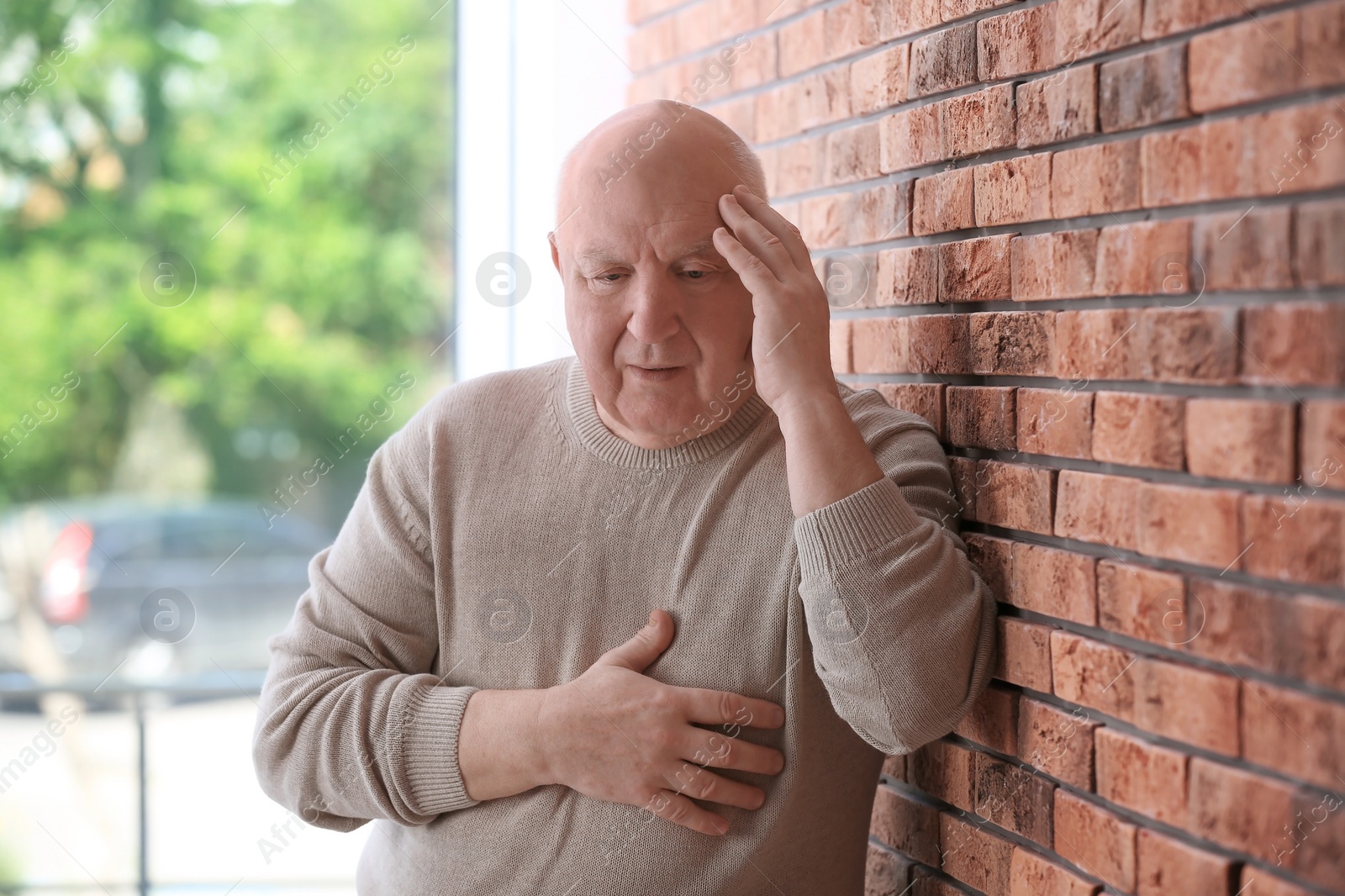 Photo of Senior man in state of depression near brick wall