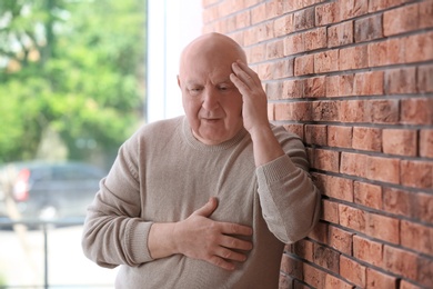 Photo of Senior man in state of depression near brick wall