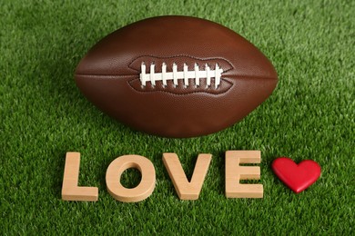 Photo of American football ball, word Love and heart on green grass