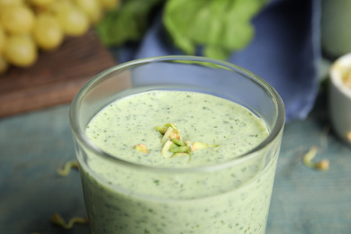 Photo of Green buckwheat smoothie on light blue table, closeup