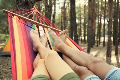 Couple resting in hammock outdoors on summer day, closeup of legs