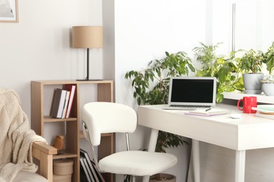 Photo of Stylish workplace with laptop on white desk near window