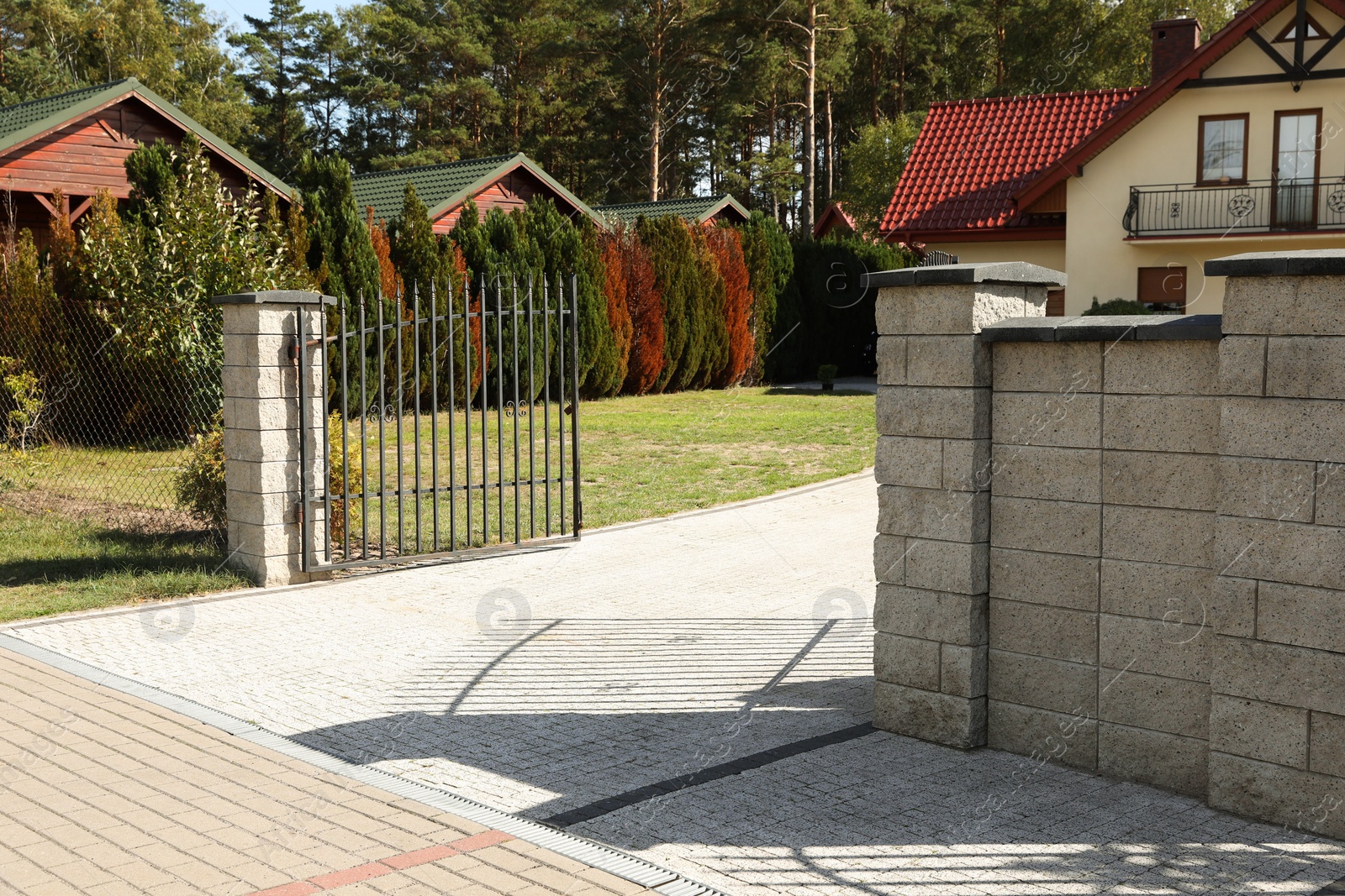 Photo of Open metal gates near houses and bushes outdoors