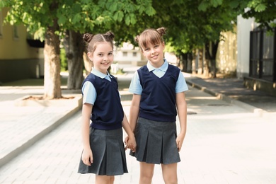 Little girls in stylish school uniform outdoors