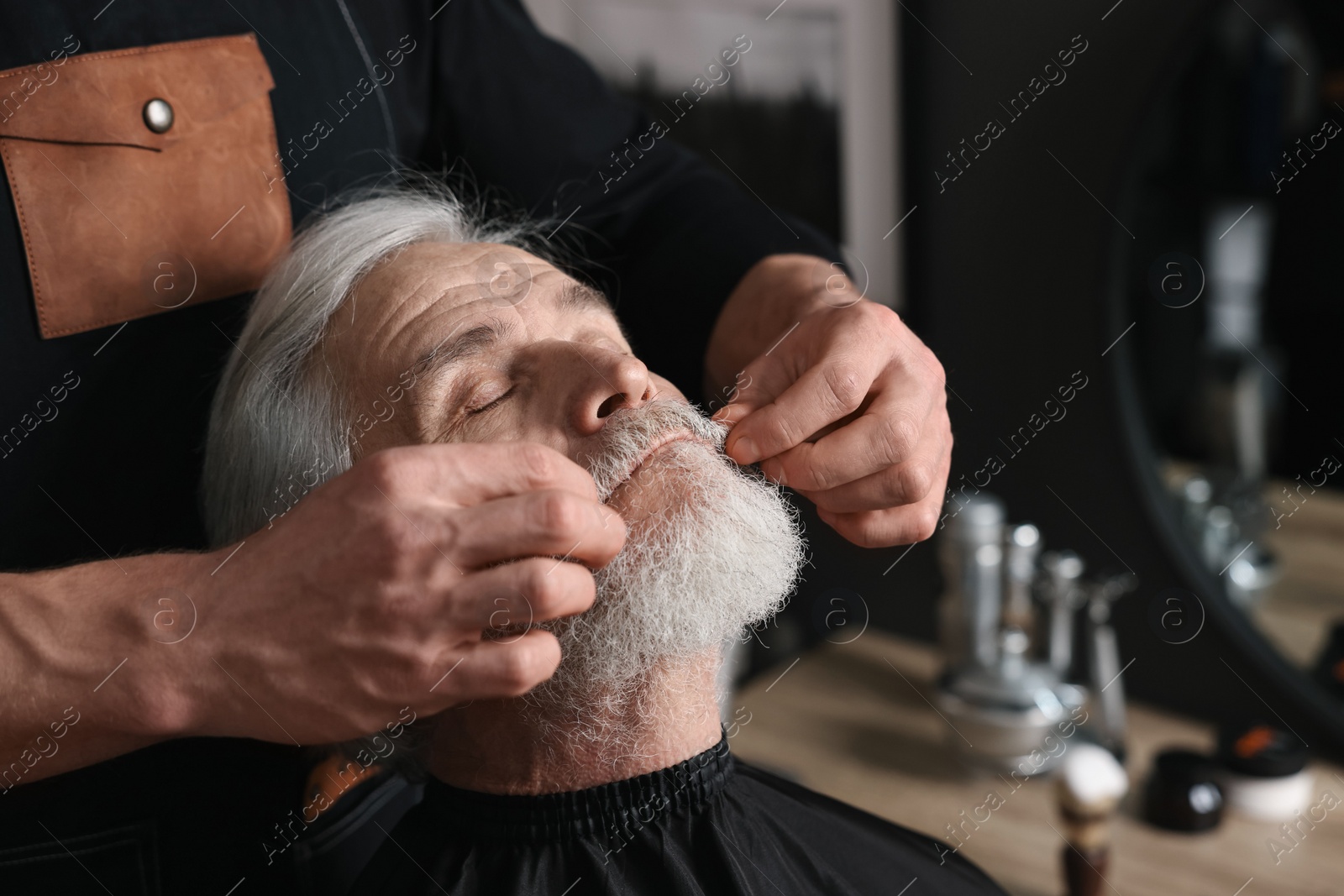 Photo of Professional barber working with client's mustache in barbershop, space for text