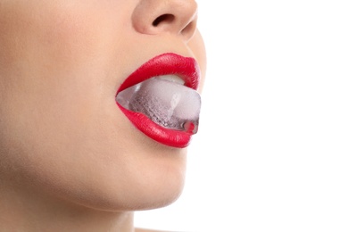 Young woman holding ice cube in mouth on white background, closeup