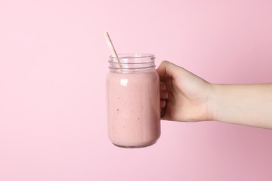 Photo of Woman holding mason jar of tasty smoothie on pink background, closeup