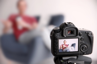 Photo of Male blogger with laptop in armchair on camera screen, closeup