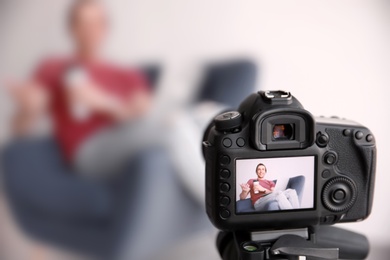 Male blogger with laptop in armchair on camera screen, closeup