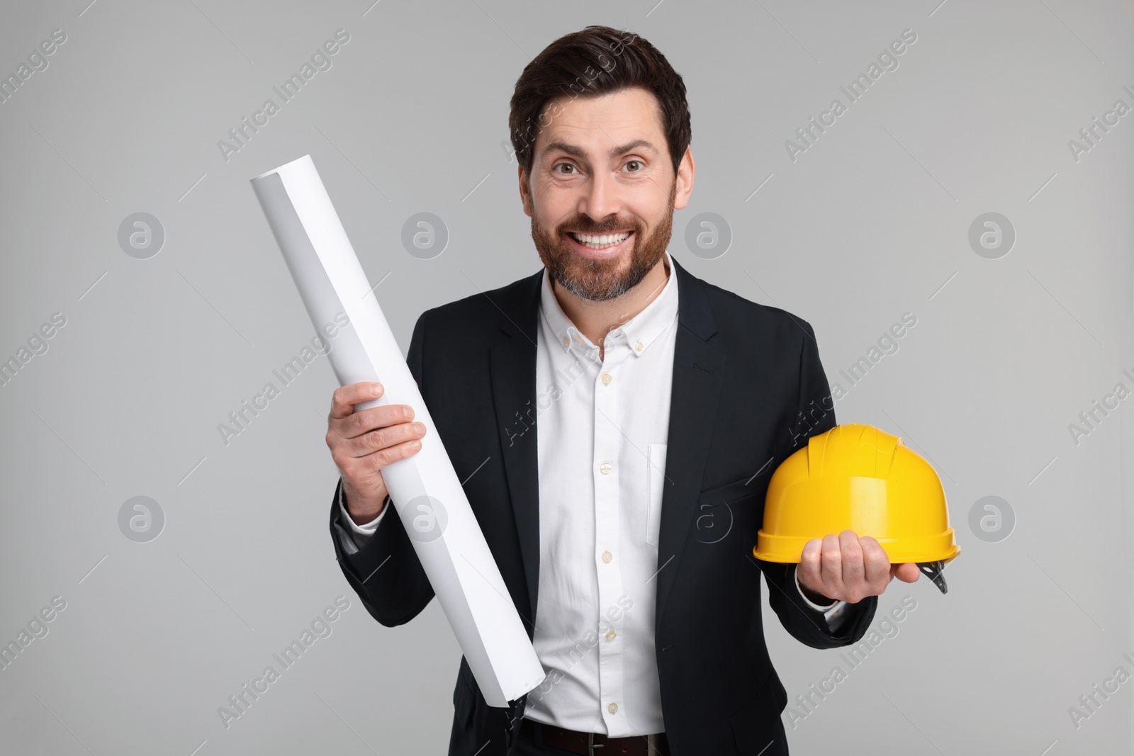 Photo of Architect with draft and hard hat on gray background