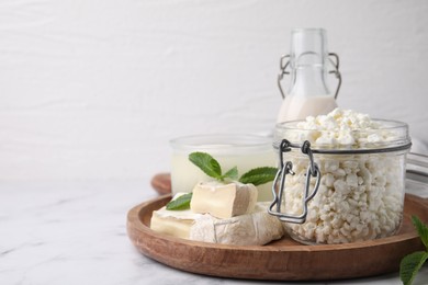 Photo of Different dairy products and mint on white marble table, space for text