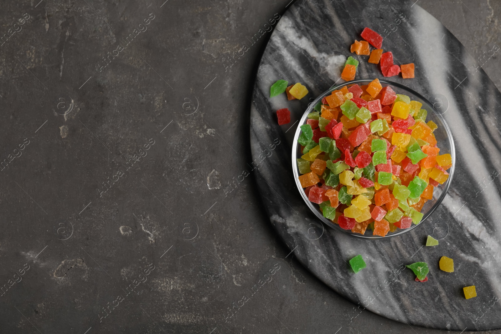 Photo of Mix of delicious candied fruits on grey table, top view. Space for text