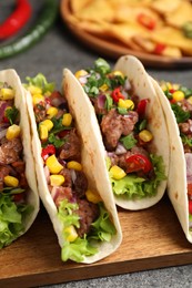 Photo of Delicious tacos with meat and vegetables on table, closeup