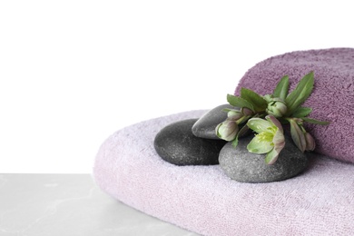 Towels, spa stones and flowers on table against white background