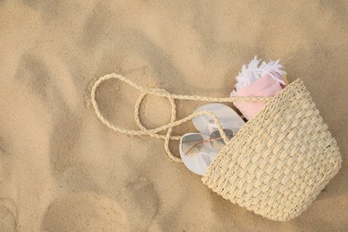 Photo of Beach bag with flip flops, towel and sunglasses on sand, top view. Space for text
