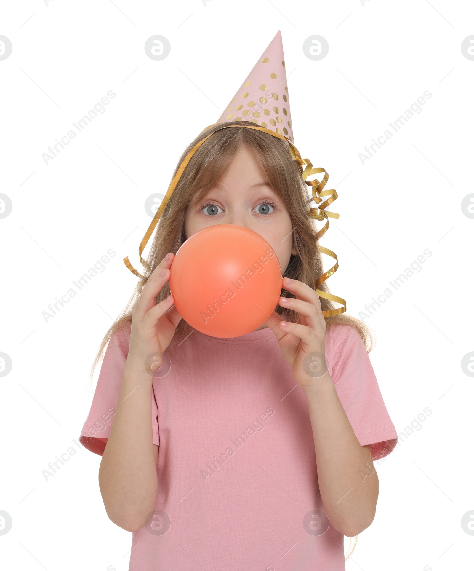 Photo of Cute little girl in party hat inflating balloon on white background
