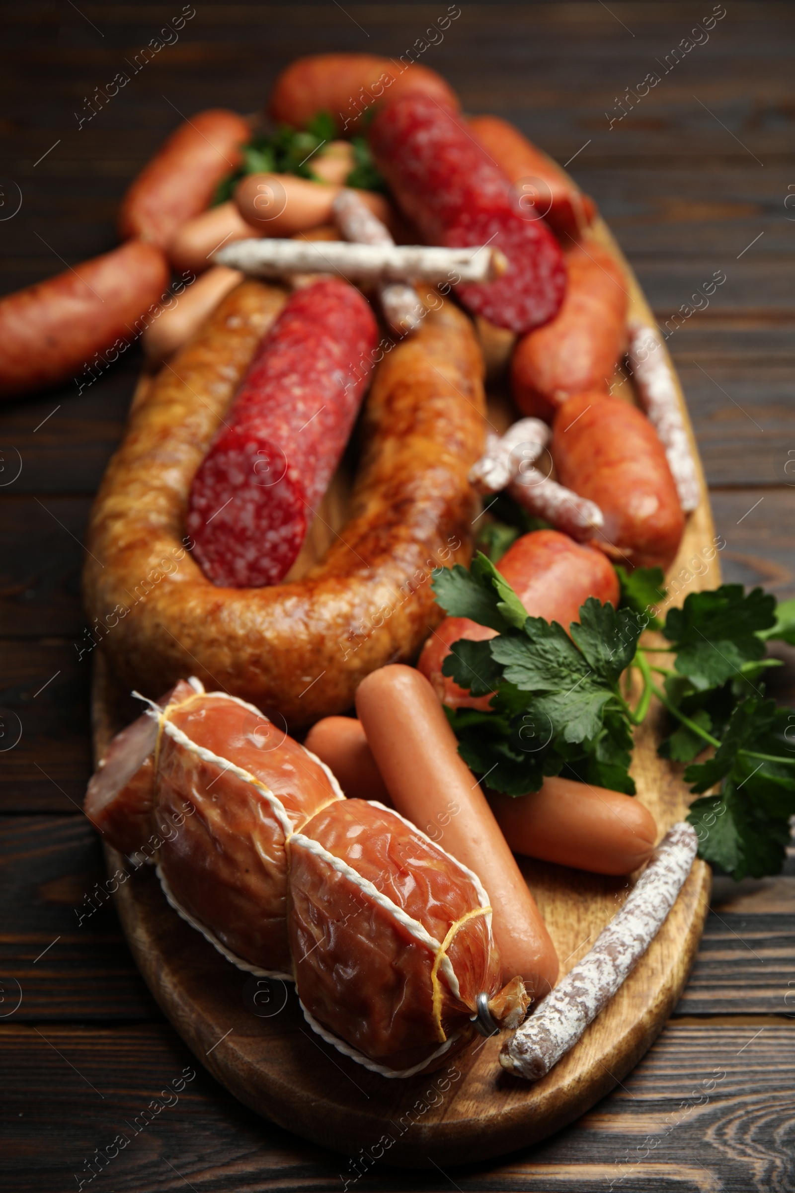 Photo of Different tasty sausages on wooden table, closeup